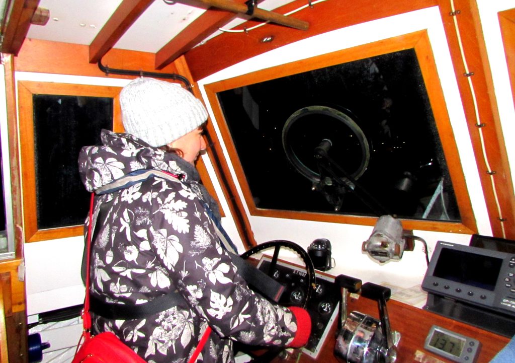 A photo of someone at the helm of Seaplane Tender 1502 in the dark. | VOS